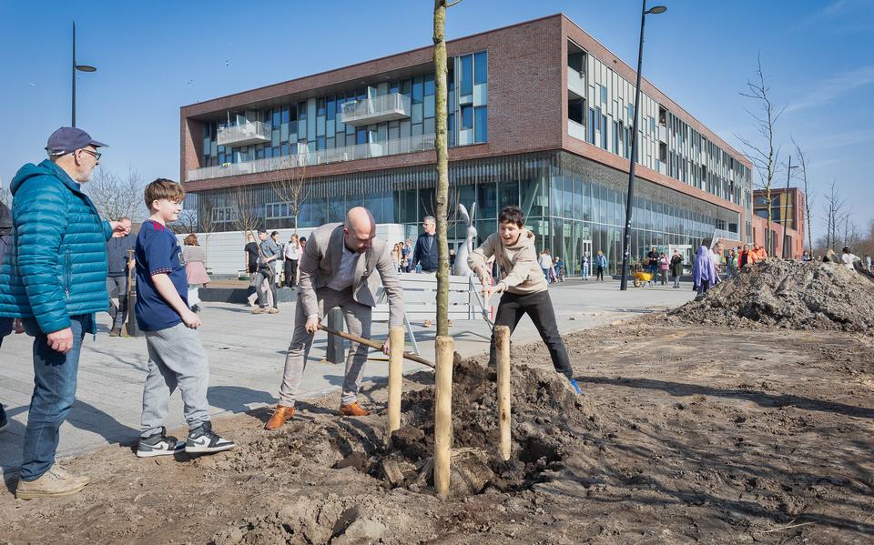 Wethouder Mark Tuit helpt met het inspitten van een boom voor mfc De Magneet. Links kijkt Lubbert Vaartjes toe.