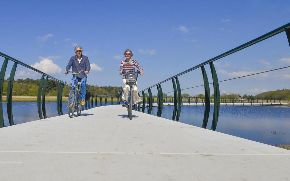 Gerard Witte en Anneke Schrama fietsen over de brug, met aan weerszijden spijlen.