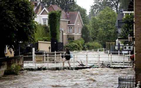 Een jonge vrouw trotseert het hoge water in Valkenburg aan de Geul bij de overstromingen van vorig jaar. 