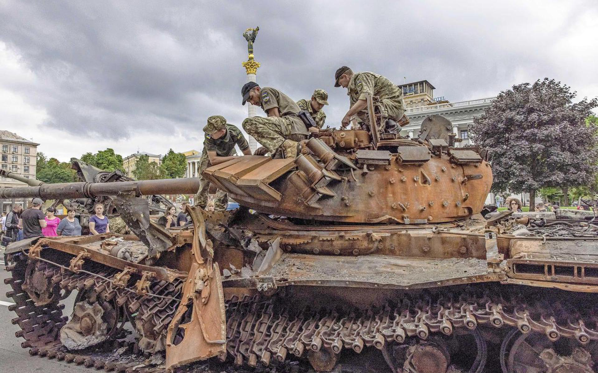 Augustus 2022: Oekraïense soldaten zitten in Kiev op een vernietigde, roestige Russische tank.