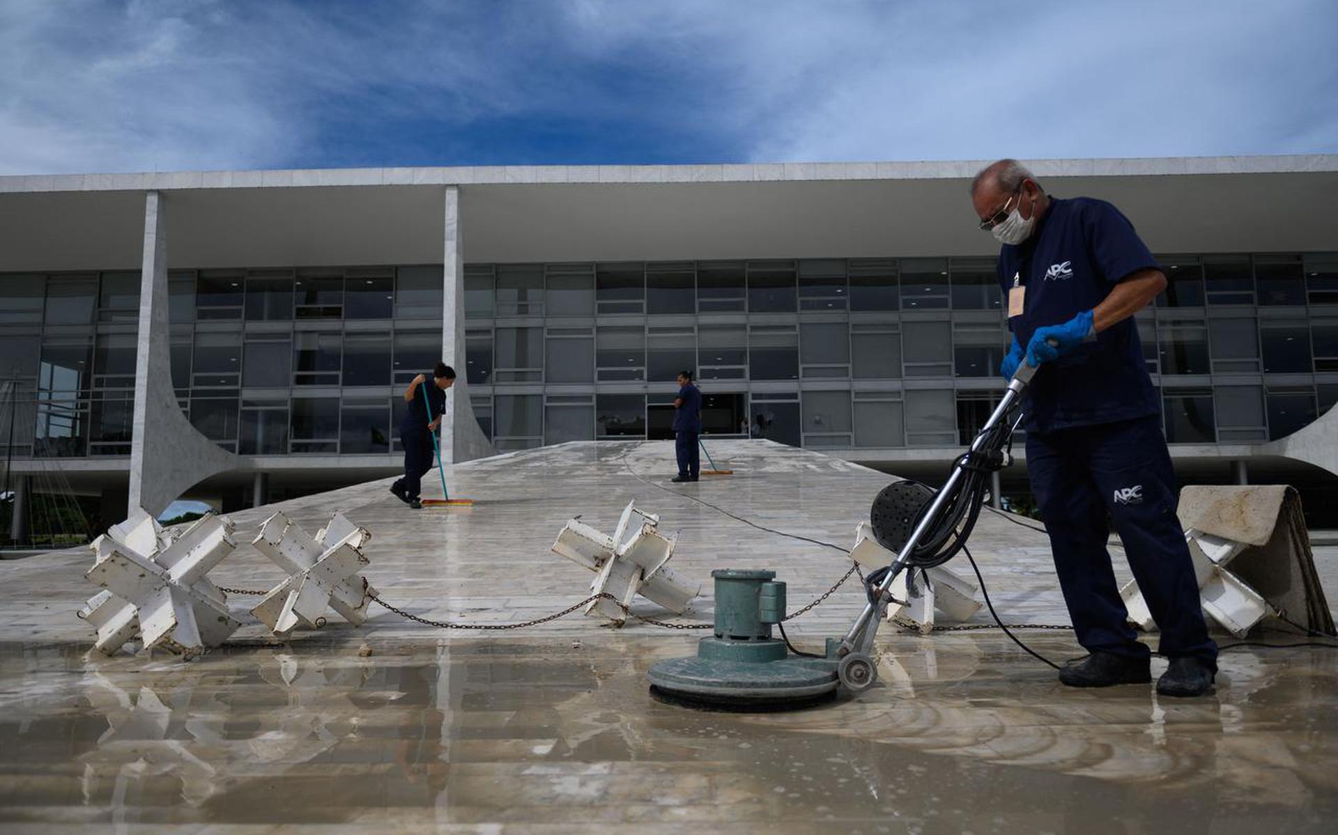 Workers polish and mop the floor during clean-up procedures at Planalto Palace in Brasilia on January 9, 2023, a day after supporters of Brazil's far-right ex-president Jair Bolsonaro invaded the Congress, presidential palace, and Supreme Court. - Brazilian security forces locked down the area around Congress, the presidential palace and the Supreme Court Monday, a day after supporters of ex-president Jair Bolsonaro stormed the seat of power in riots that triggered an international outcry. Hardline Bolsonaro supporters have been protesting outside army bases calling for a military intervention to stop Lula from taking power since his election win. (Photo by MAURO PIMENTEL / AFP)