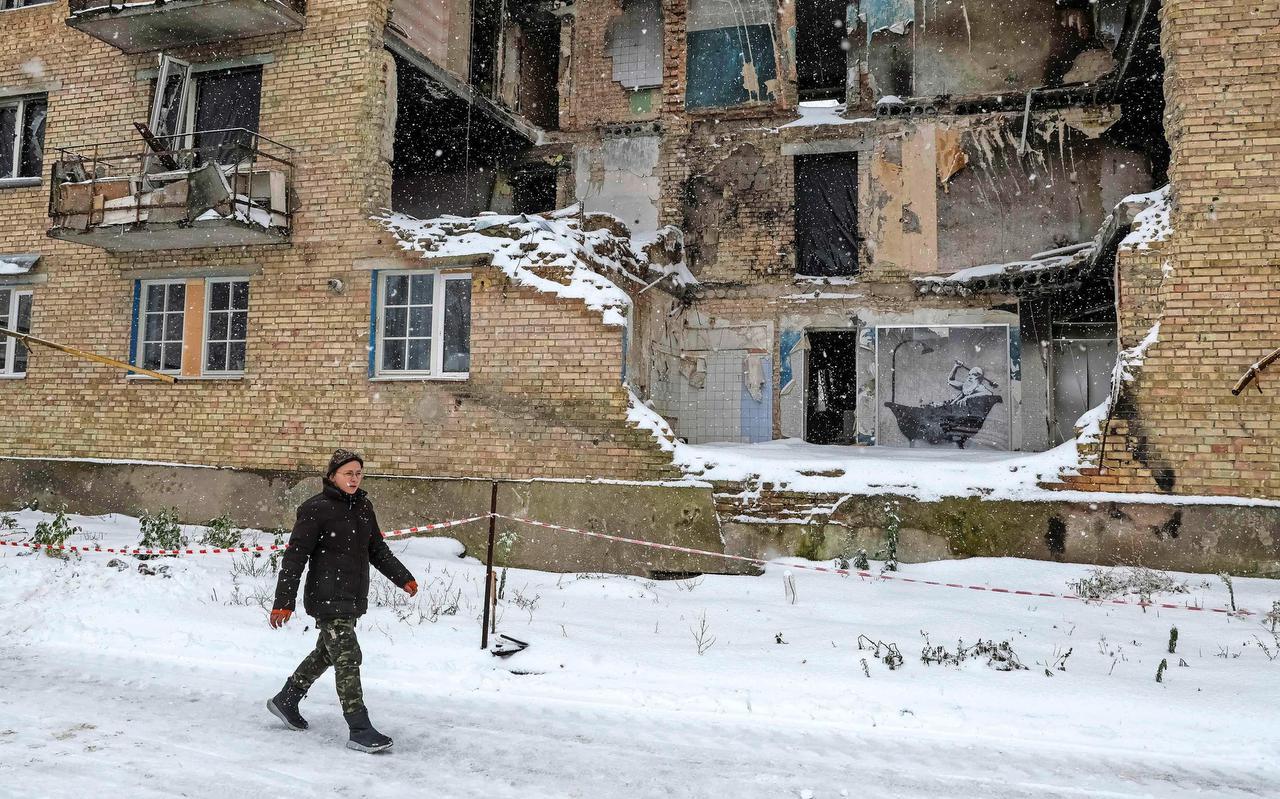 Sneeuw valt op de weggeslagen gevel van een flatgebouw dat bij een Russische aanval is geraakt.