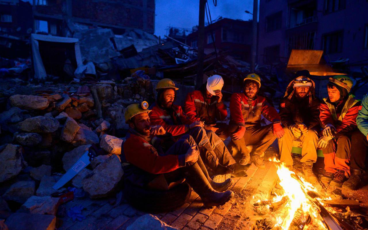 Reddingswerkers warmen zich rond een kampvuur in Hatay.
