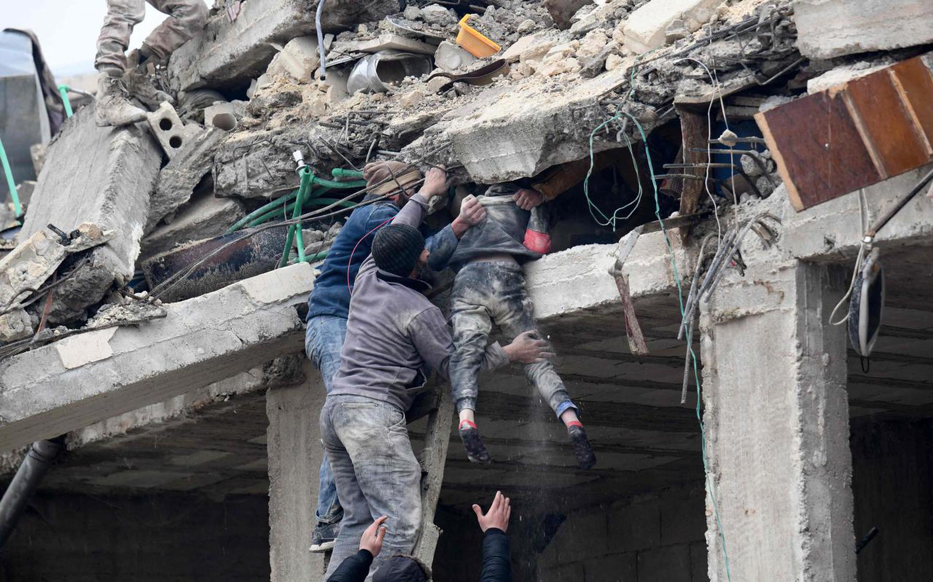 Reddingswerkers halen een gewond meisje uit de brokstukken van een ingestort gebouw in Jandaris, in Syrië.