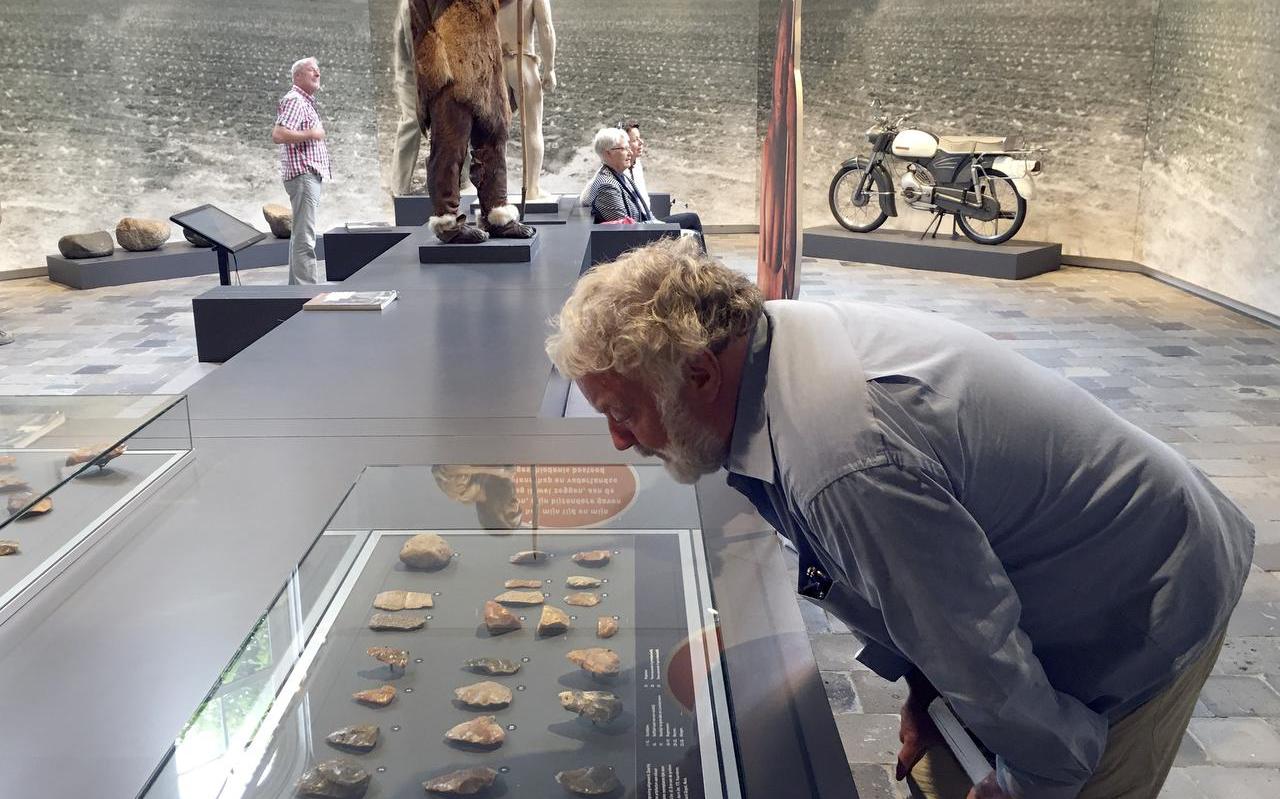 Archeoloog Dick Stapert buigt zich over een vitrine met echte neanderthalerwerktuigen. Foto DvhN

