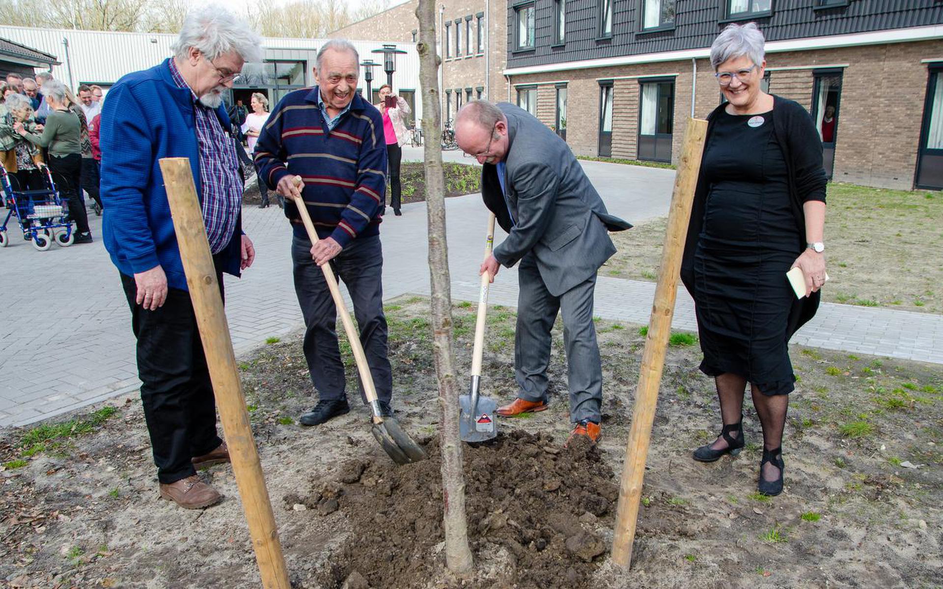 Cor Dontje en burgemeester Klaas Smid planten een boom. IJsbrand van der Leeuw van de cliëntenraad en zorgmanager Heleen Rietsema kijken toe.