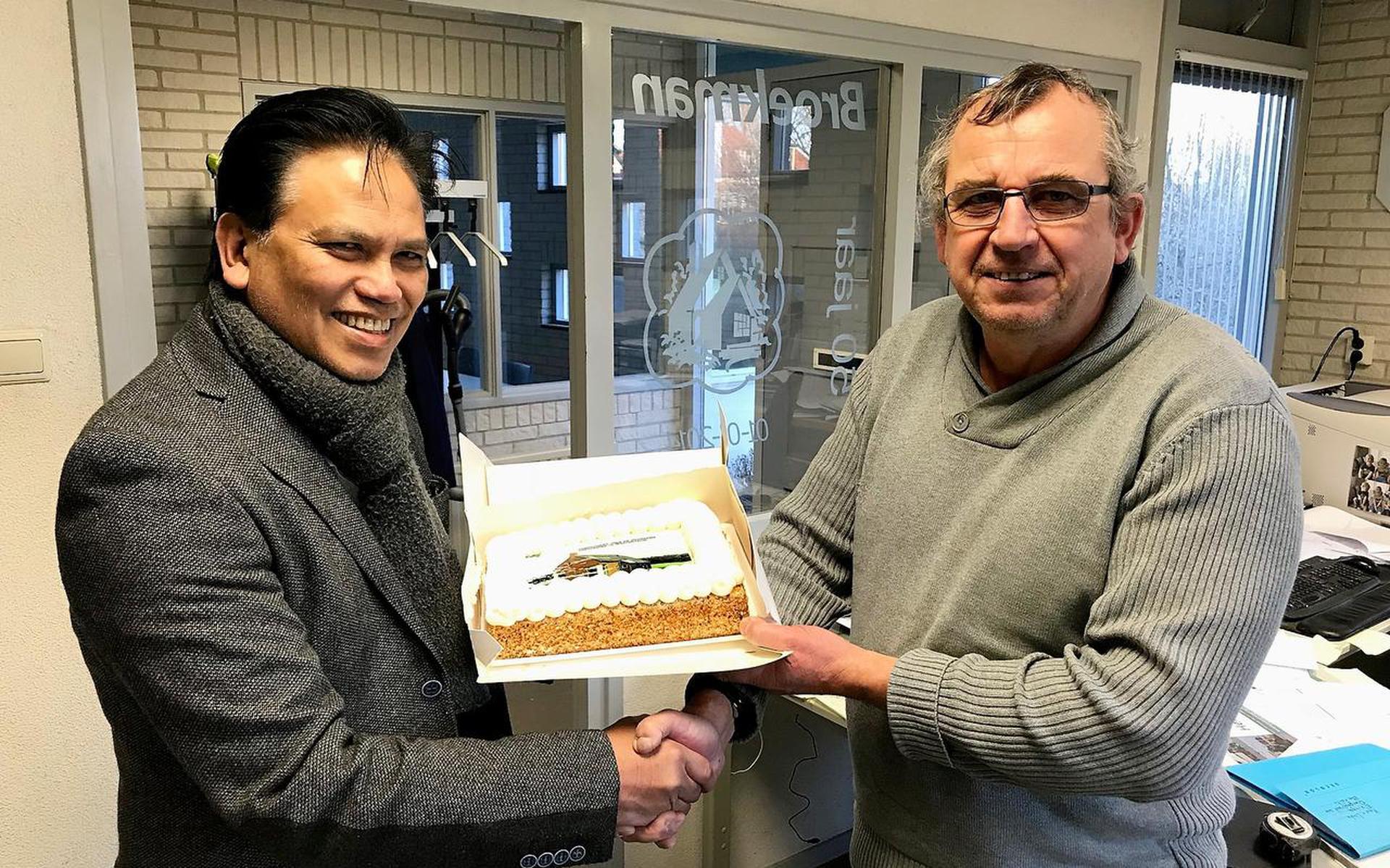 Henri Jansen (links) overhandigt de pluim in de vorm van een taart aan aannemer Hilco Broekman. Foto DvhN
