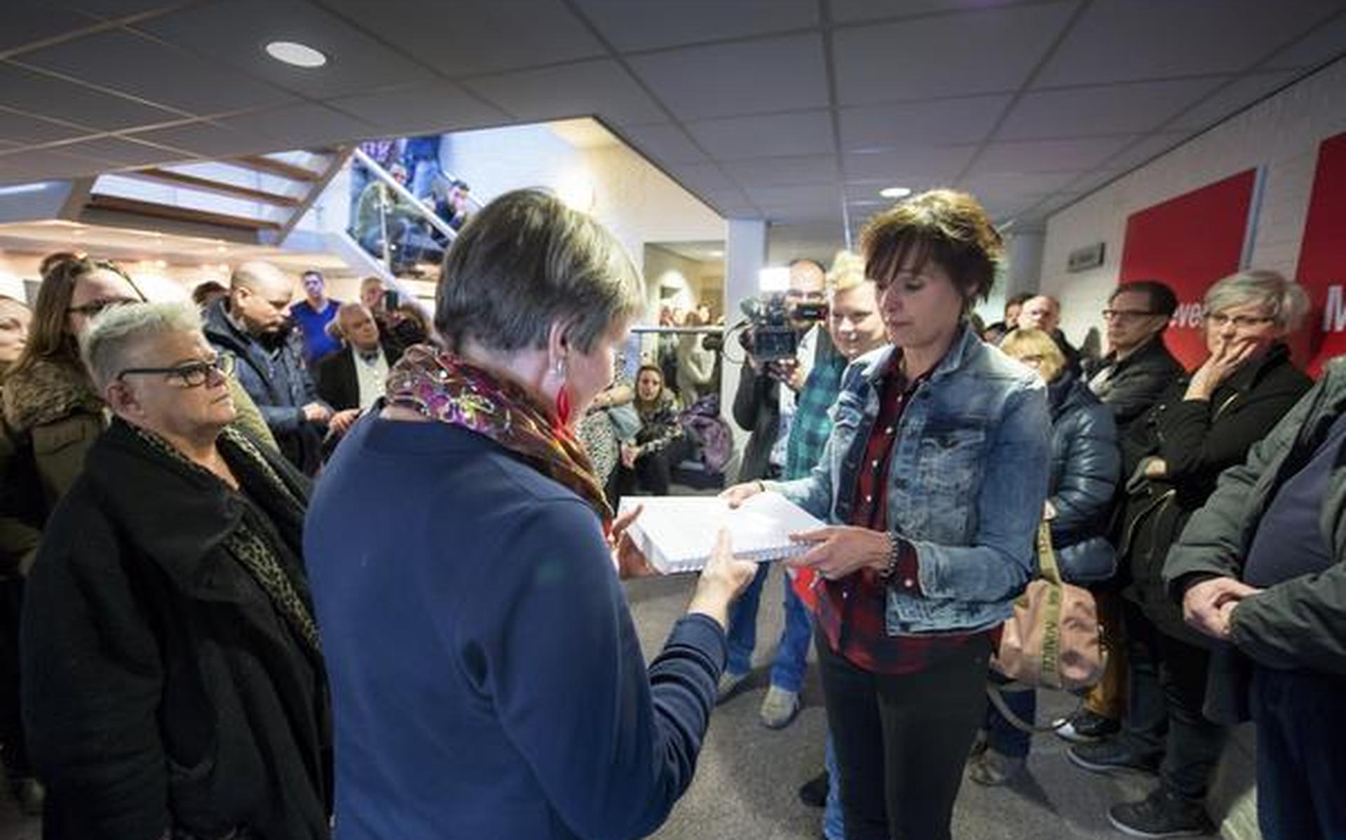 Medewerkers bieden Janny Vlietstra zo'n 1100 handtekeningen aan. FOTO HILBRAND DIJKHUIZEN