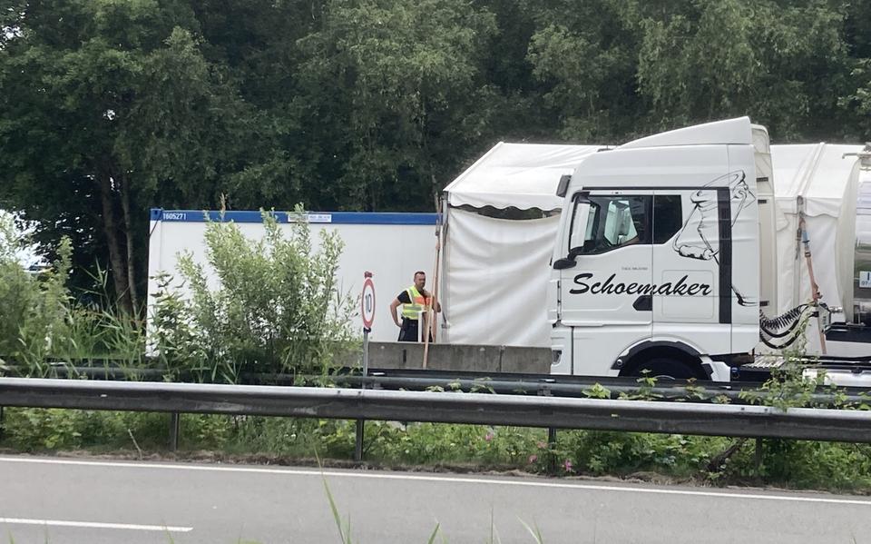 Een Duitse beambte controleert een vrachtwagen die langzaam langs de douanepost rijdt.