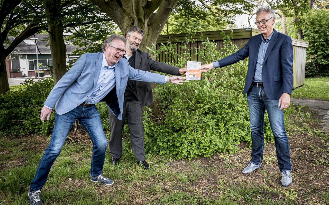 Egbert Dommerholt (links) en Derwin Schorren overhandigen op veilige afstand hun boekje aan Siem Jansen van het Nationaal Programma Groningen. 