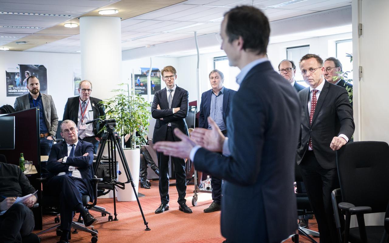 Minister Wiebes (op de rug gezien) en minister Dekker (midden met bril) op de nieuwe locatie van de Tijdelijke Commissie Mijnbouwschade in Groningen. Minister Wiebes (op de rug gezien) en minister Dekker (midden met bril) op de nieuwe locatie van de Tijdelijke Commissie Mijnbouwschade in Groningen.