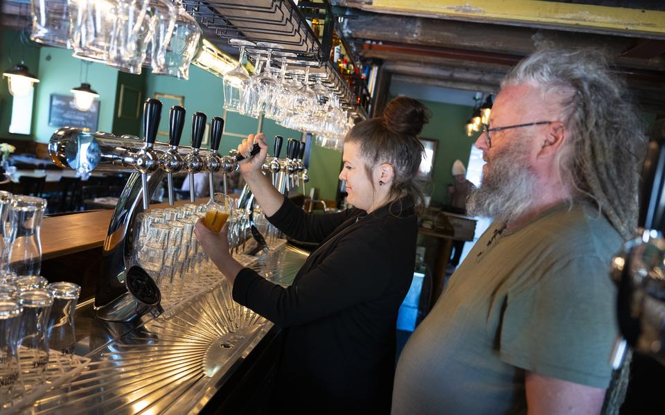 Lotte van der Stelt tapt een L'Hopster Goud in het nieuwe proeflokaal van de dorpsbrouwerij in Loppersum. Haar man Mark kijkt toe.
