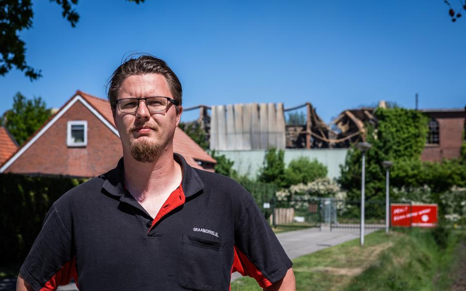Bert Jan de Boer van dierenwinkel De Graankorrel in Oude Pekela met op de achtergrond de door brand verwoeste vezelhennep opslag. 