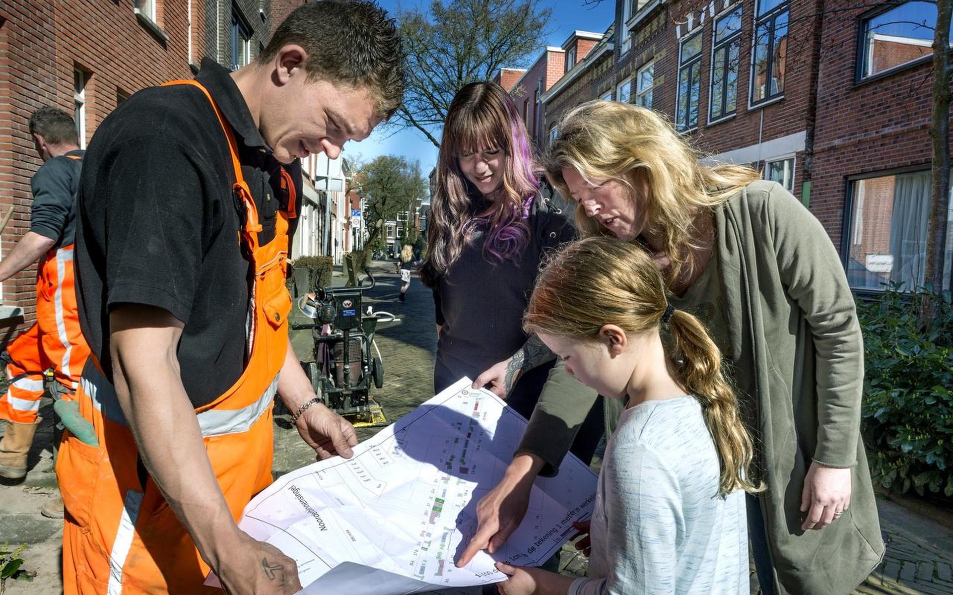 Tanja Meijer (rechts) en Josephine van de Beld bekijken met stratenmaker Mark en Merel (7) de plannen voor de aanpassingen in de Grote Appelstraat. Foto Peter Wassing
