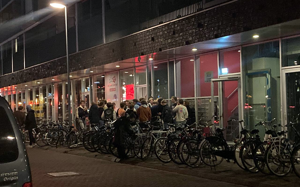 Buiten rondhangende studenten bij de grote rij fietsen waarmee ze gekomen zjin.