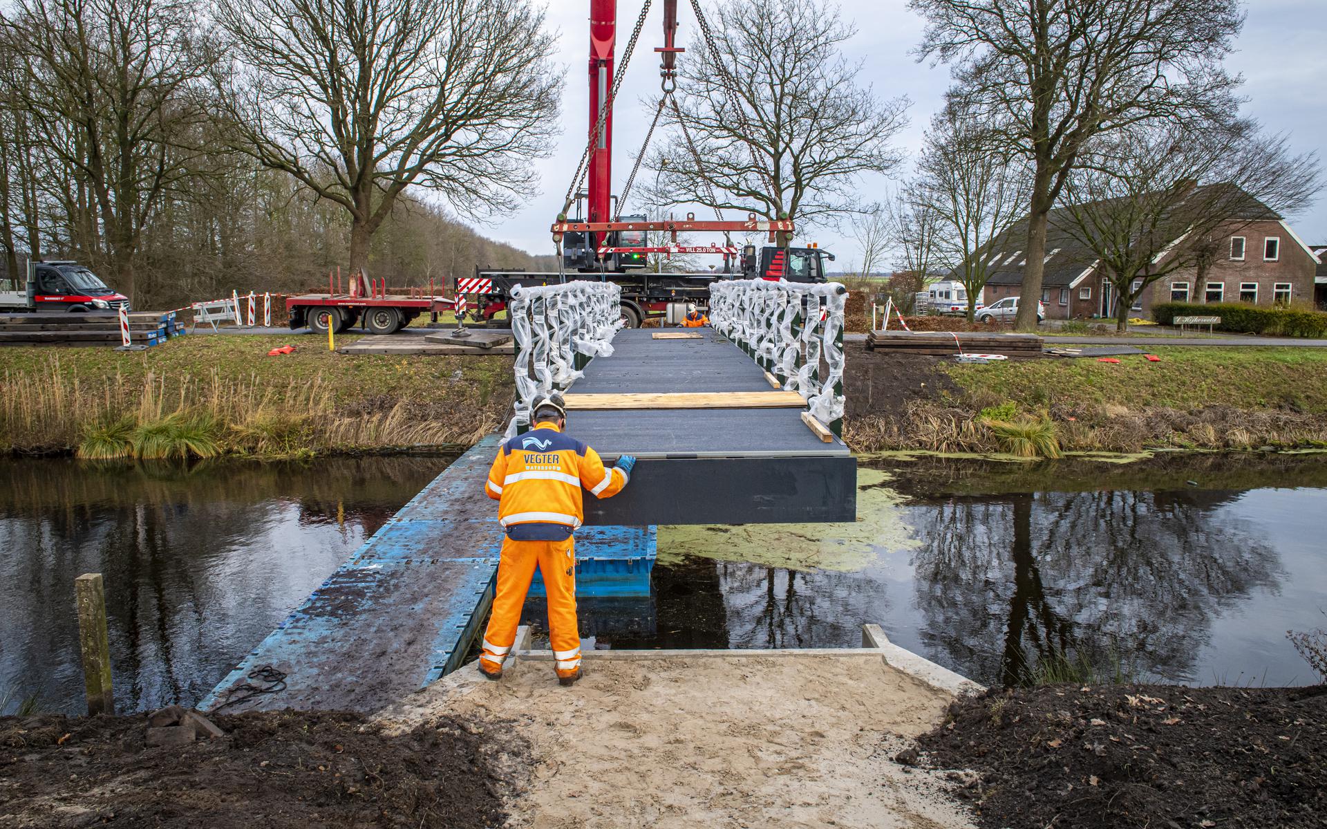 De nieuwe voetgangers- en fietsbrug over het Oranjekanaal in Hijken wordt op z'n plek gehangen.  Foto Marcel Jurian de Jong.
