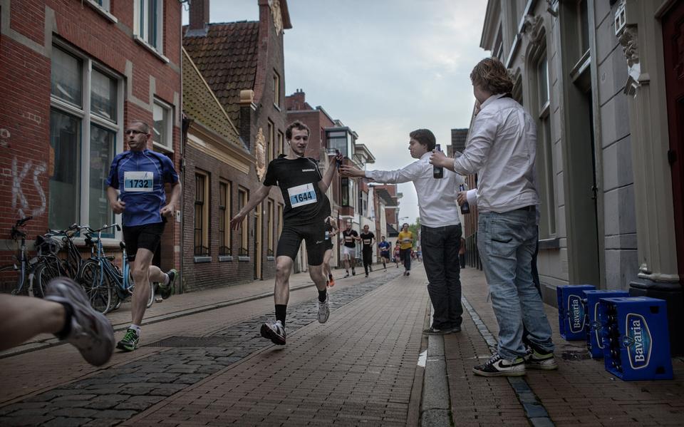 Tijdens hardloopevenement de Nacht van Groningen bieden studenten van studentenvereniging Albertus Magnes de lopers een biertje aan.