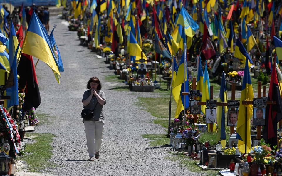 Een vrouw loopt tussen de graven op de militaire begraafplaats in Lviv.