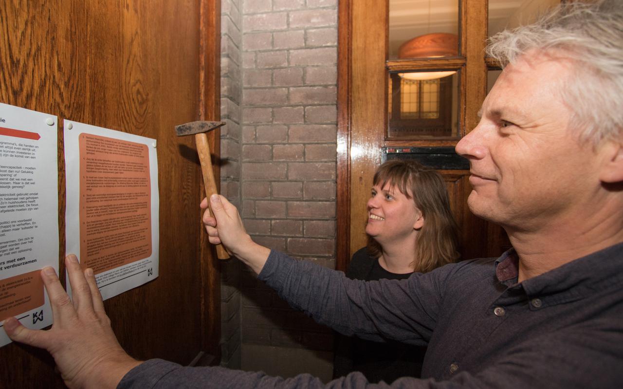 Marco van Dalfsen en Marlies Hesselman spijkeren de Recht op Energie verklaring op het prikbord van het voormalige kantongerecht aan de Kattenhage in Groningen. Foto: DvhN