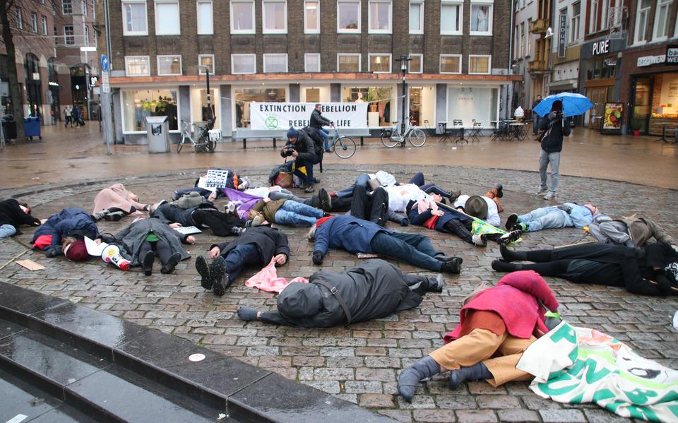 Demonstranten van Extinction Rebellion houden zich 'dood' op de Vismarkt in Groningen tijdens de test van het luchtalarm.