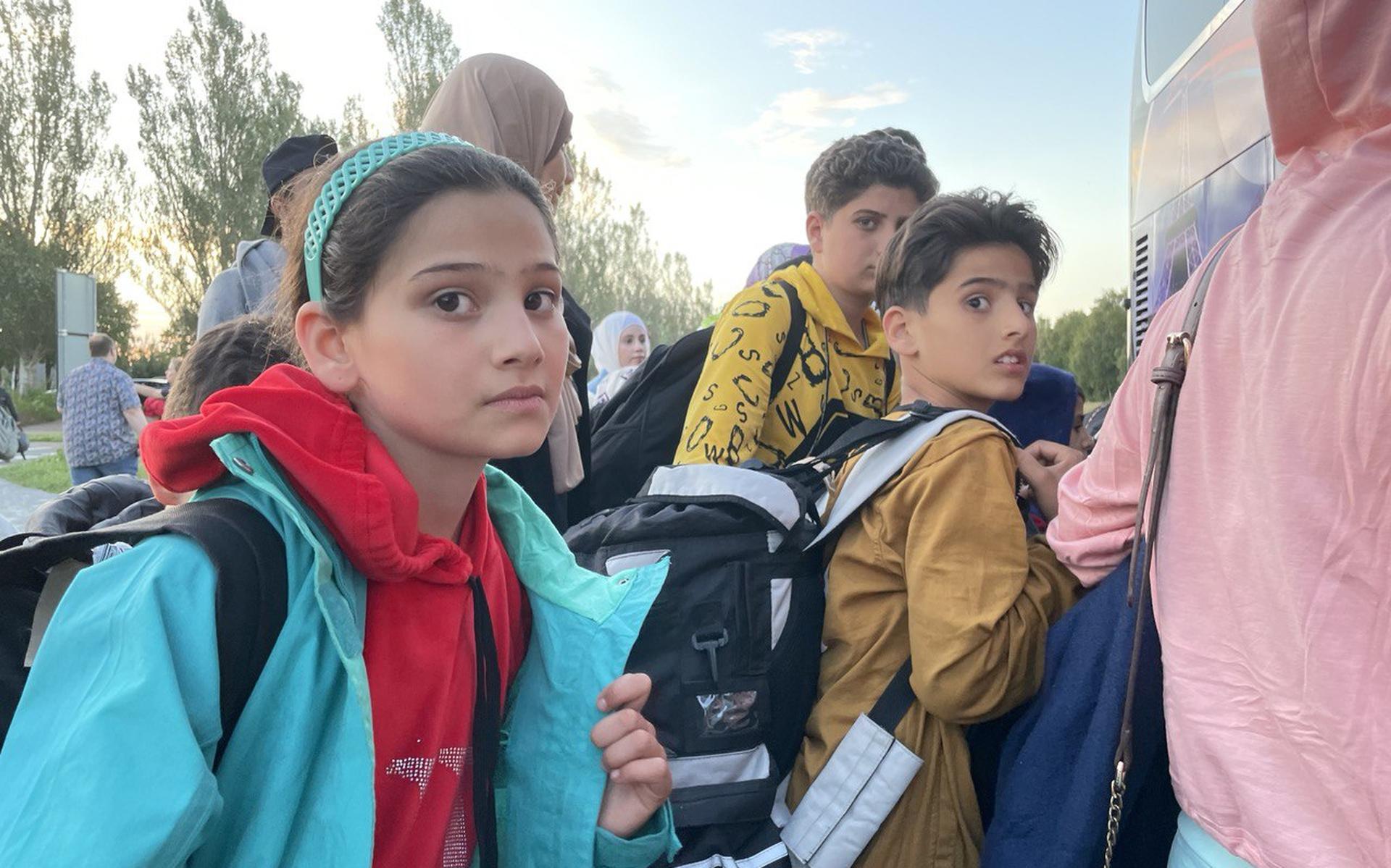 Kinderen worden na een lange dag wachten naar een andere locatie gebracht.