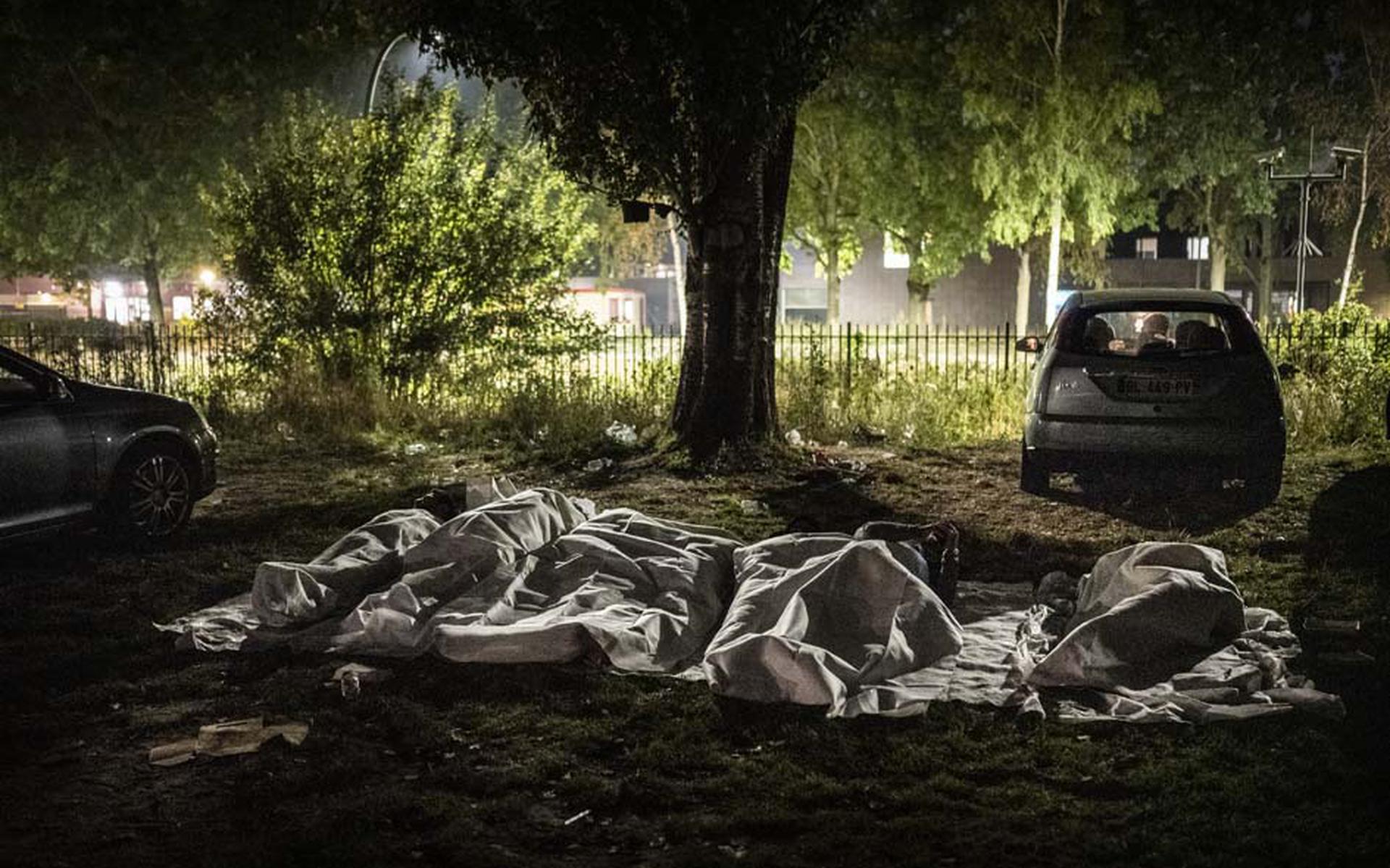 De voor de Zilveren Camera Publieksprijs genomineerde foto van Kees van de Veen: Mannen slapen in de nacht van 23 augustus 2022 buiten op een parkeerterrein vlakbij het aanmeldcentrum in Ter Apel.