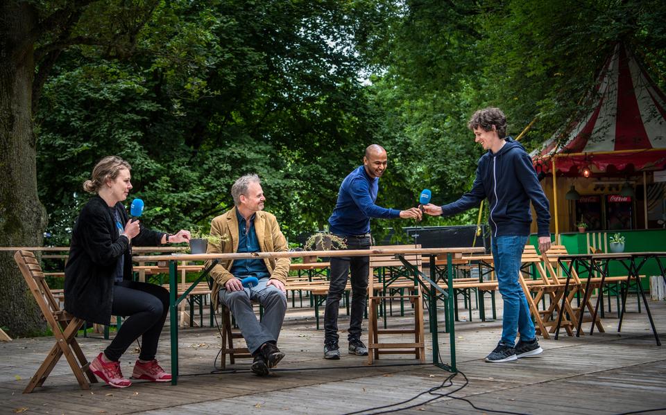 Performance-artiest Simon Senn (rechts) neemt tijdens Zomer Live de microfoon over van taalkunstenaar Ahilan Ratnamohan. Uiterst links presentator Leonie Sinnema en naast haar Mark Yeoman (artistiek directeur Noorderzon).