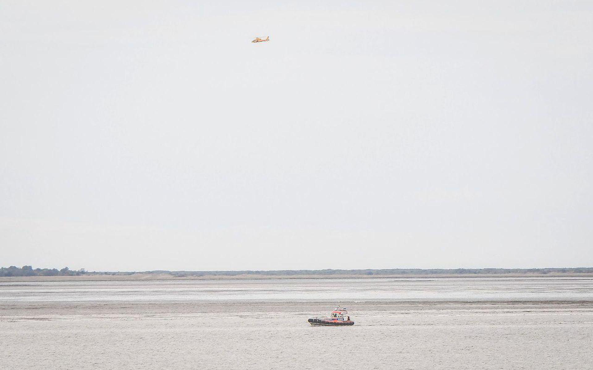 Een boot van de KNRM en een helikopter zoeken op het wad naar drie kano's. Foto: De Vries Media