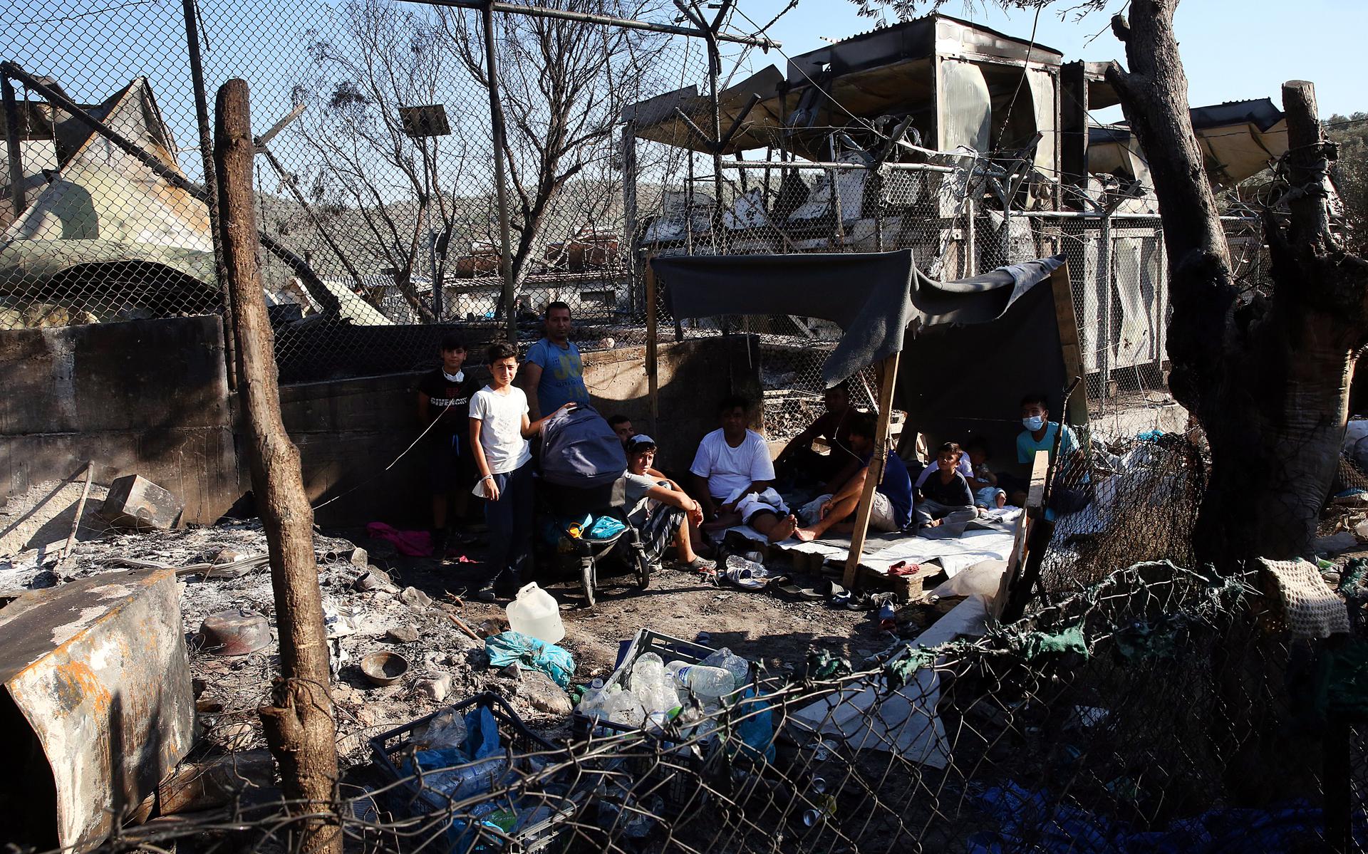 Vluchtelingen tussen de uitgebrande restanten van het vluchtelingenkamp Moria op Lesbos. 