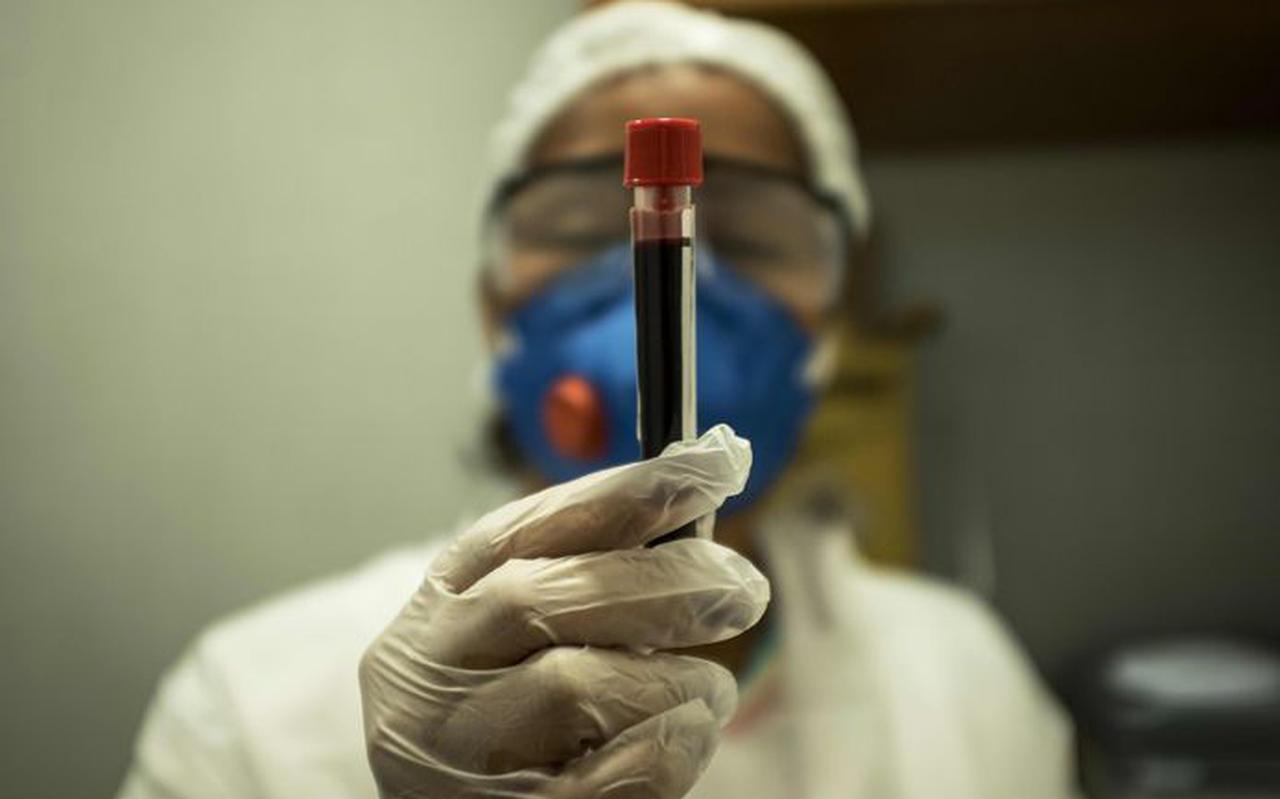 Een verpleegster houdt een buisje bloed vast. 