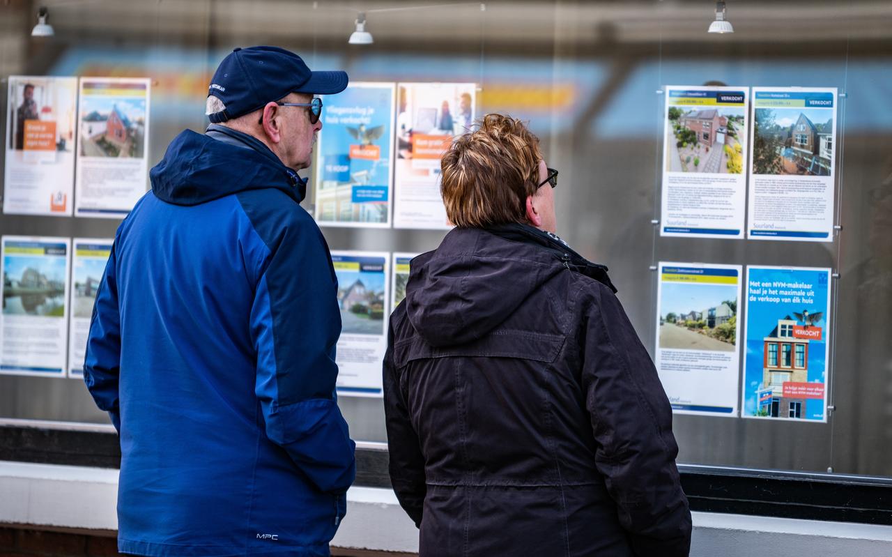 Mensen kijken naar te koop staande woningen bij een makelaar. Mensen kijken naar te koop staande woningen bij een makelaar.