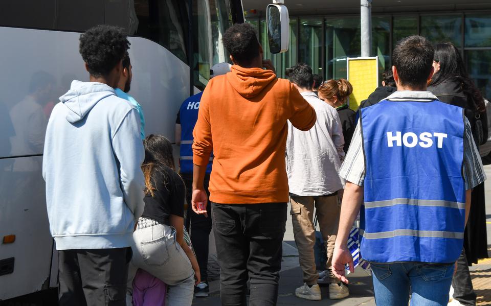 Hosts helpen asielzoekers op het station in Emmen bij de bus naar Ter Apel 