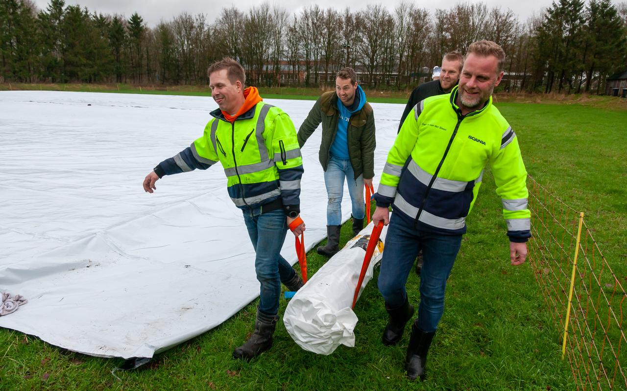 De bestuursleden van V.V.V.O. lopen met een rol landbouwplastic, de nieuwe ondergrond van wat de ijsbaan moet worden. Foto Gerrit Boer De bestuursleden van V.V.V.O. lopen met een rol landbouwplastic, de nieuwe ondergrond van wat de ijsbaan moet worden. Foto Gerrit Boer