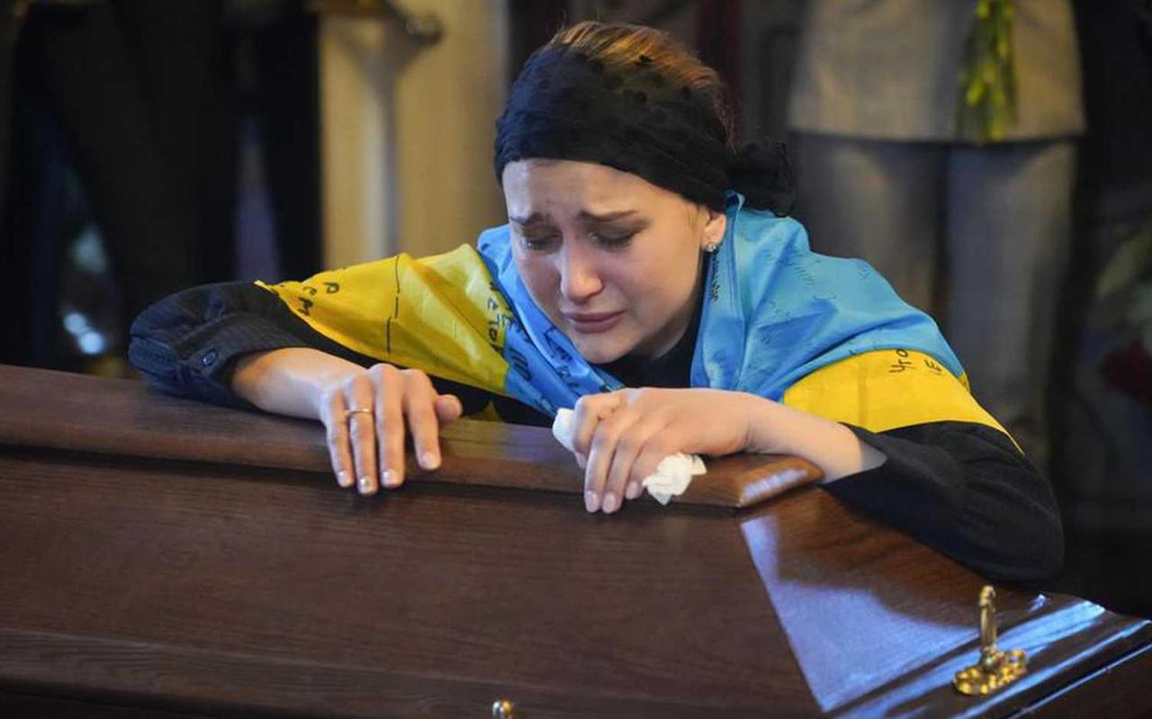 Een huilende vrouw bij de doodskist van haar man, die werd gedood door Russische soldaten. Foto: AP
