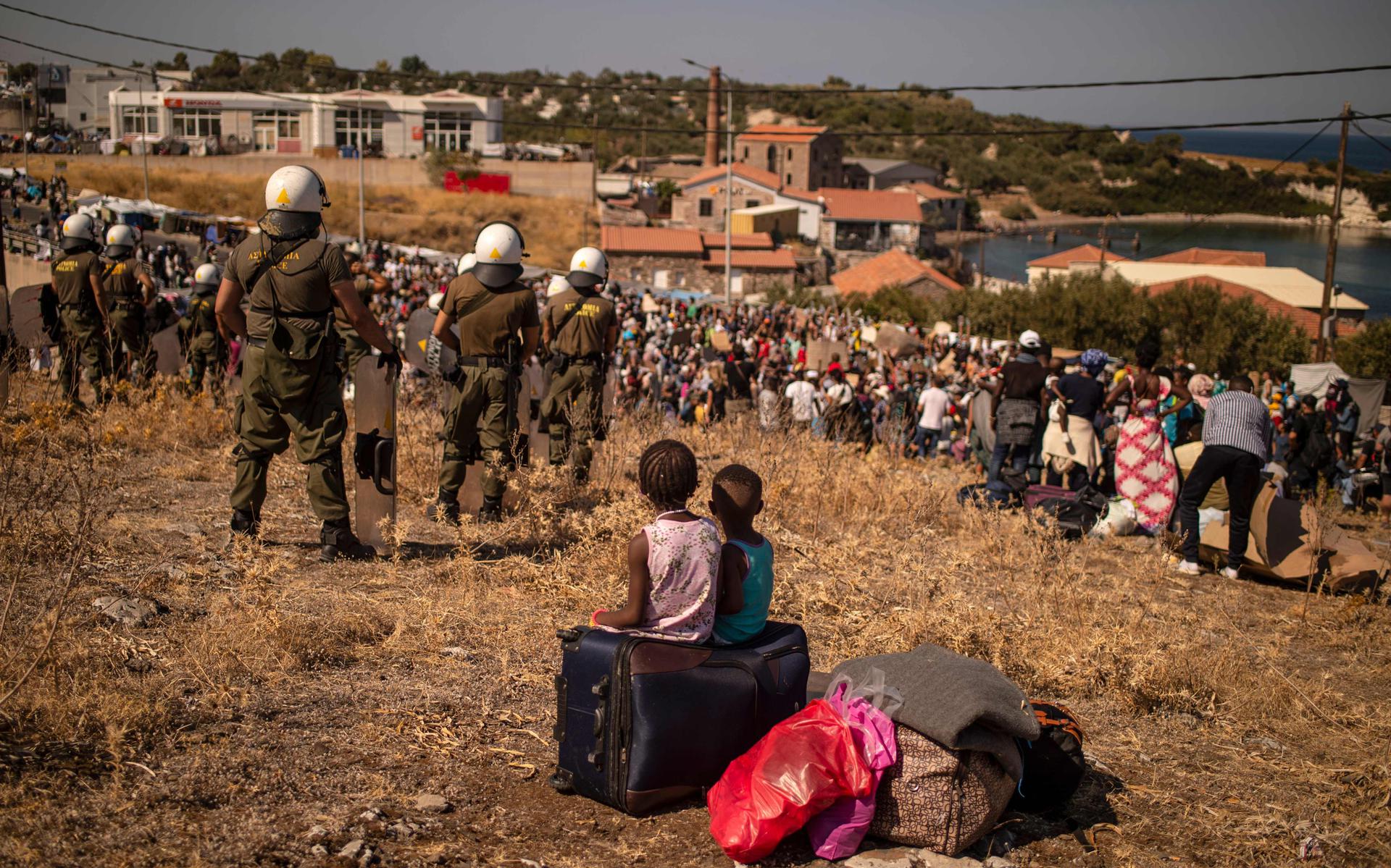 Twee meisjes kijken toe hoe andere vluchtelingen uit het kamp bij Moria protesteren, een paar dagen nadat het kamp werd verwoest door brand.