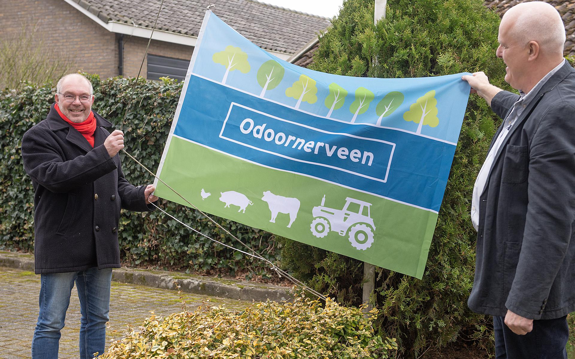De onthulling  van de dorpsvlag door wethouder Henk Zwiep (links) en dorpsvoorzitter Eisso Kronenberg.
