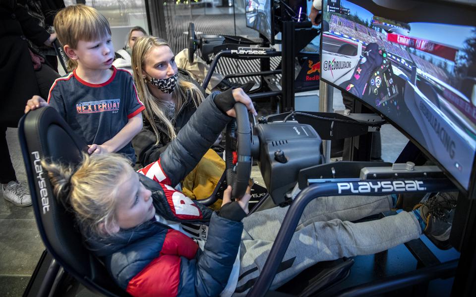 Jorn (10) zit in een van de twee race-simulators van het Forum Groningen. Z'n broertje Nils en z'n oppas kijken toe.