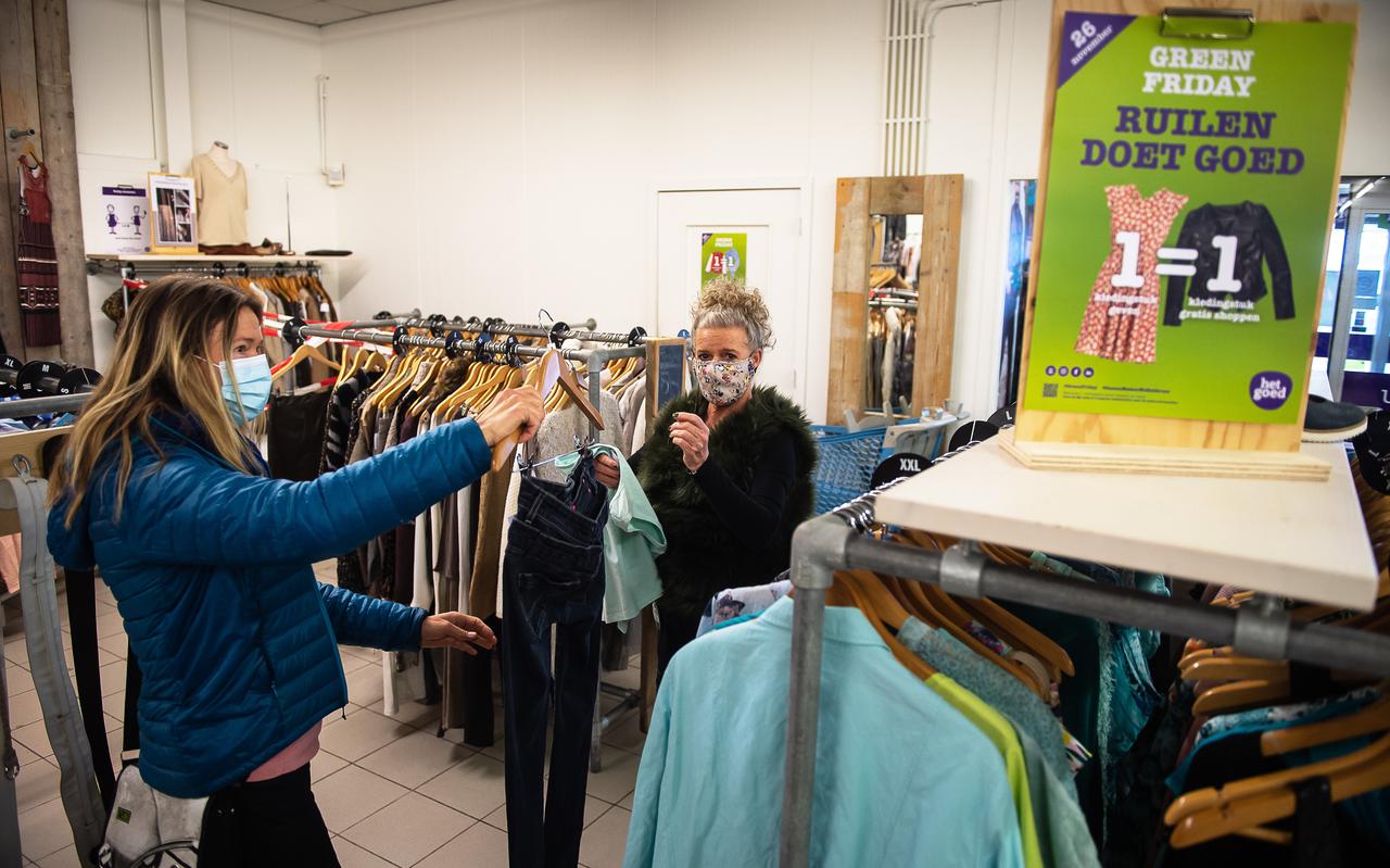 Het Goed-medewerkster Deborah Philips (rechts) helpt een klant met het uitzoeken van kleding.