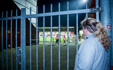 Een eenzame supporter probeert vanachter de hekken een glimp van haar geliefde FC Emmen op te vangen. De Drentse eerste divisionist beschouwt de afwezigheid van publiek op de tribunes als een bom die onder het verdienmodel is gelegd. Dat staat in het jaarverslag van het seizoen 2020/2021.
