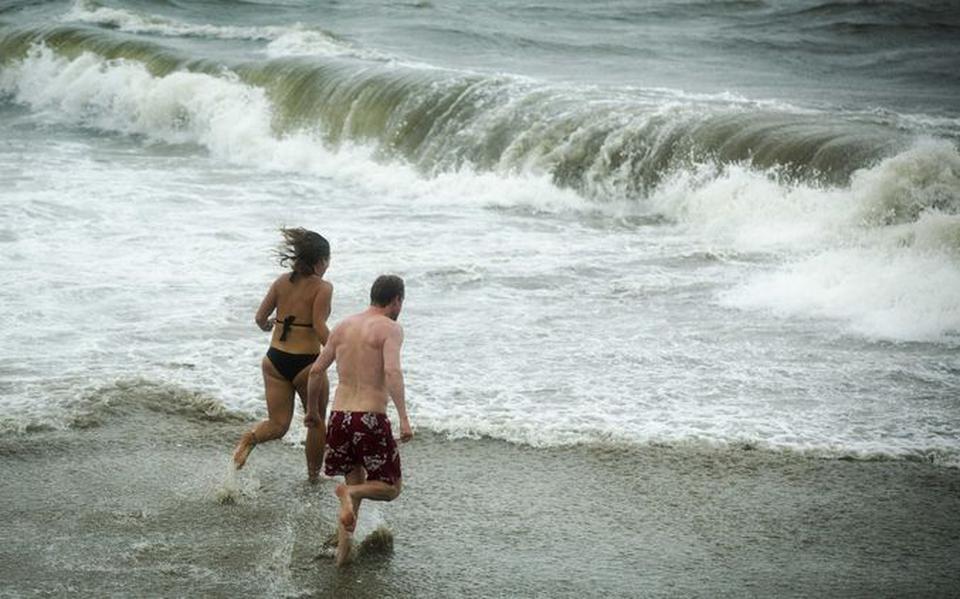 Ondanks regen en hevige windstoten nemen een man en vrouw een duik in zee. 