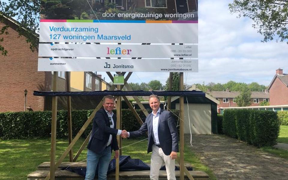 Bouwer en opdrachtgever schudden elkaar de hand bij de onthulling van het bouwbord.