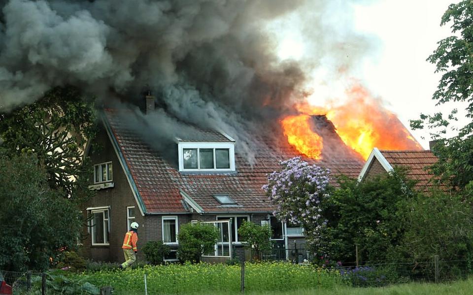 Een brand heeft een woonhuis en een schuur aan de Kerkweg in Tiendeveen in de as gelegd. De brandweer is druk bezig met blussen.
