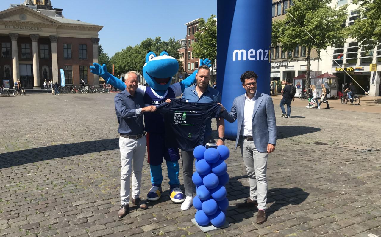 Mascotte Timey helpt Johan Meijer van Golazo (midden), Rob de Waard (links) van het Jeugdfonds en Stefan Raats van Menzis met de start van de 4 Mijl-inschrijving op de Vismarkt.