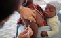 Een Zuid-Afrikaanse baby kijkt toe hoe zijn moeder wordt geprikt. Vaccins lijken voor mildere klachten te zorgen bij besmetting met de omikronvariant.