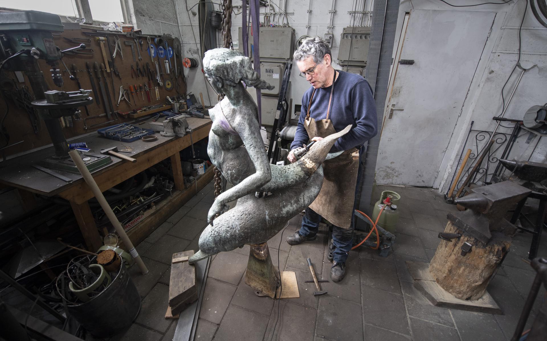 Smid Fred Bos repareert twee bijzondere kunstwerken. Een bronzen Zeemeermin en koperen oorlogsmonument De Vlam