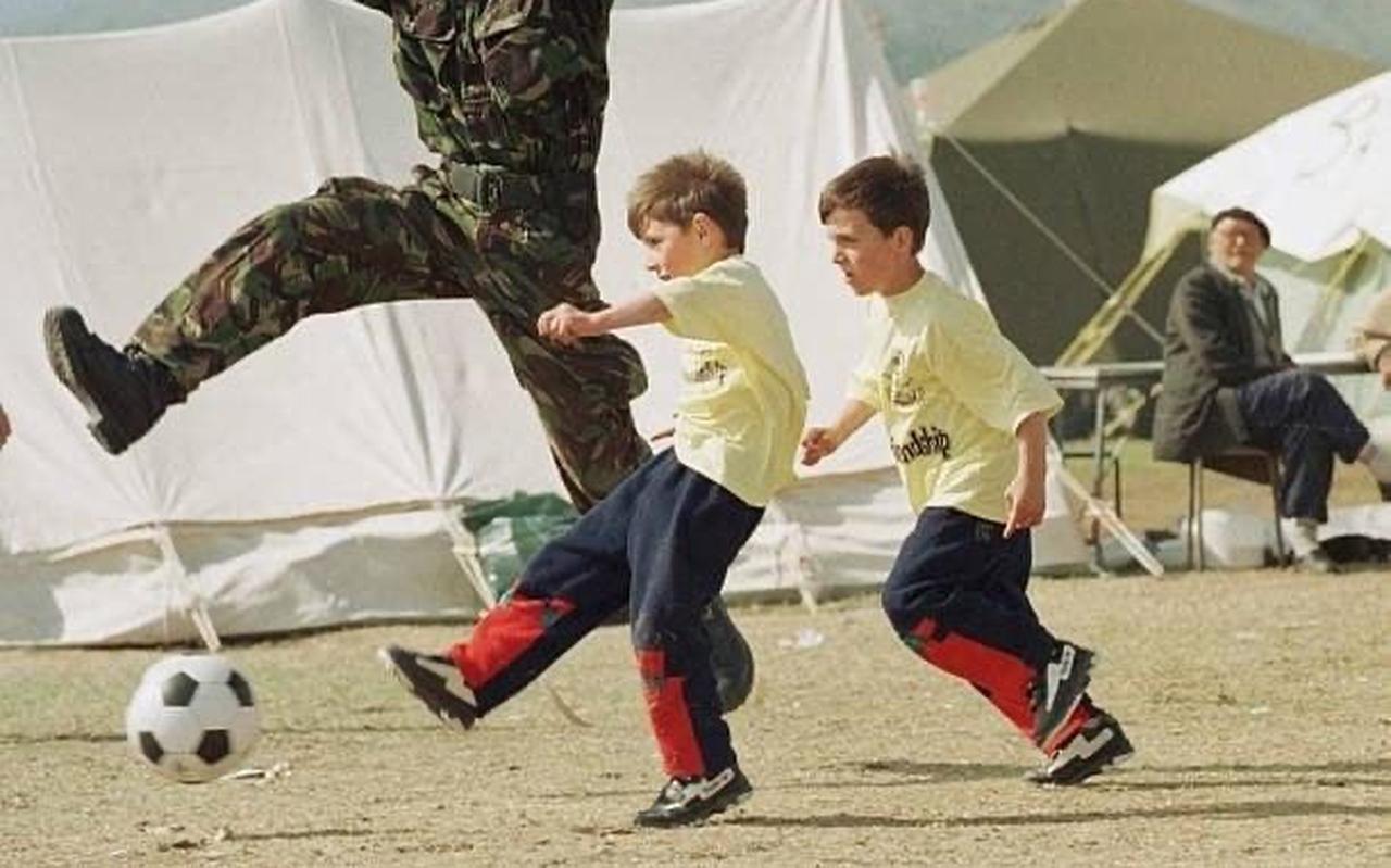 Getuar (midden) en Erolind (rechts) met een militair tijdens een potje voetbal in het vluchtelingenkamp in Macedonië. Getuar (midden) en Erolind (rechts) met een militair tijdens een potje voetbal in het vluchtelingenkamp in Macedonië.