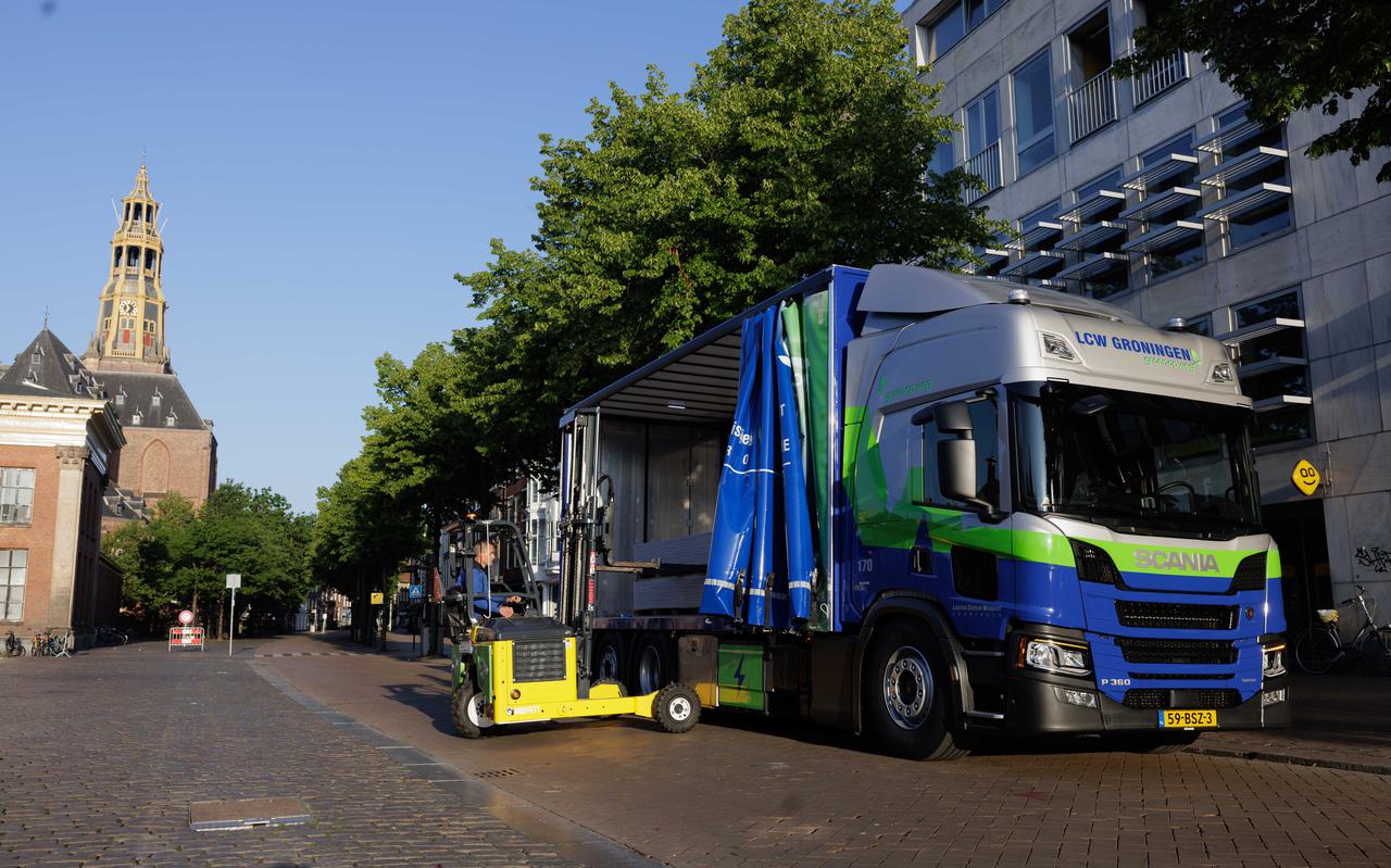 De hybride vrachtwagen, geschikt voor buitenmaatse bouwmaterialen, rijdt elektrisch in de binnenstad van Groningen.