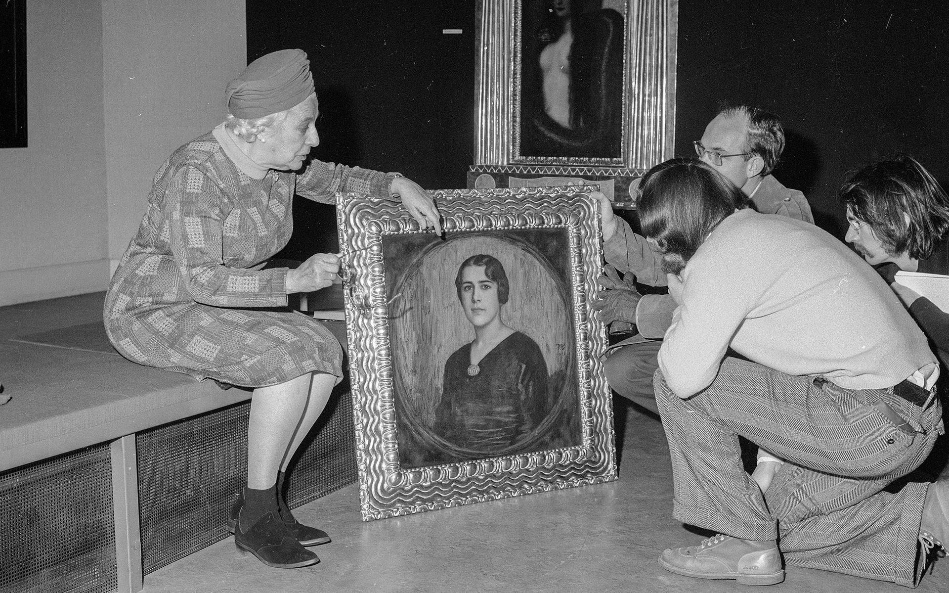 Henk van Os (rechts, het portret vasthoudend) en Bert Treffers (knielend voor het portret) van de tentoonstelling 'Het geheim'.
