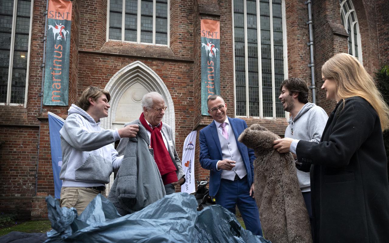 Beheerder van de Martinikerk Jan Haak (blauw pak) en directeur van de Open Hof Gerhard ter Beek (rode sjaal) nemen de jassen in ontvangst van Vindicat-leden Adriaan Zoetmulder (links), Laurens van Buren (rechts) en Janne van Waveren (rechts). 