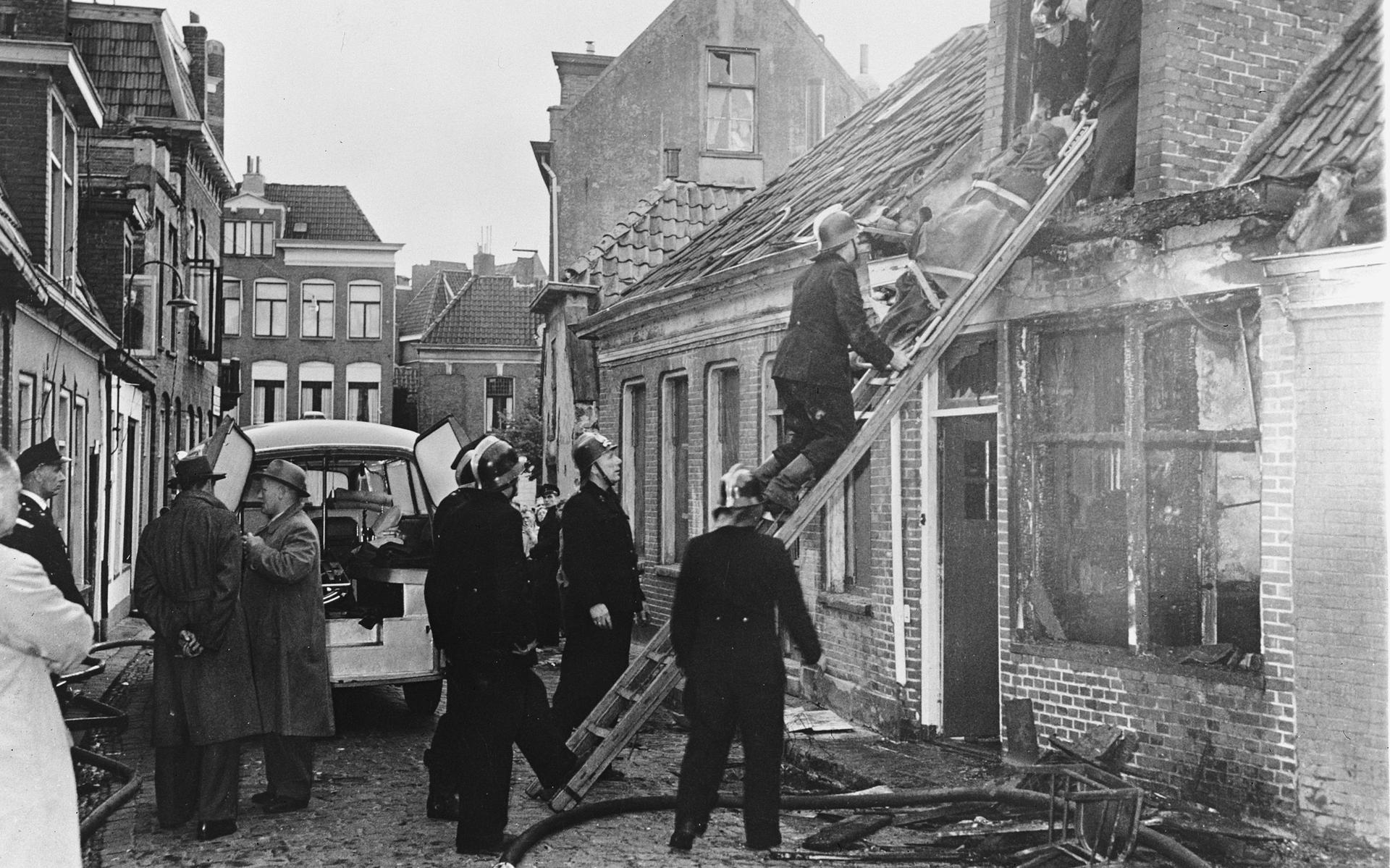 Het drama aan de Driemolendrift in Groningen op 2 juni 1958. Een van de stoffelijke overschotten wordt uit het huisje op nummer 6 naar buiten gehaald. 